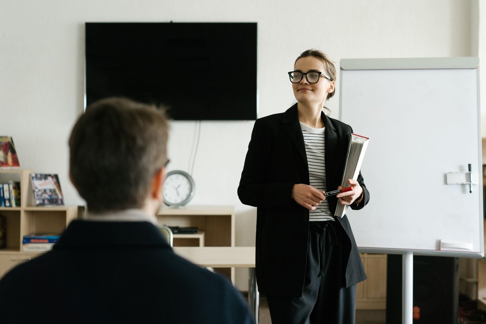 A woman presents at a whiteboard while a colleague listens in an office