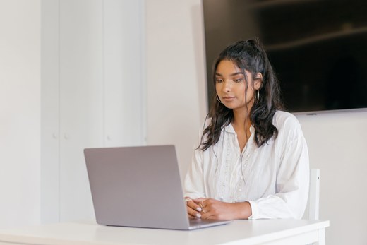 A woman works focused at a laptop in a minimalist office