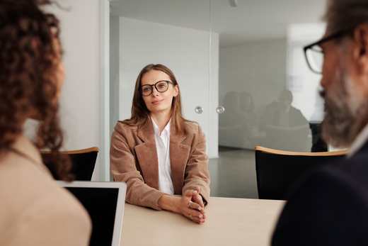 A candidate sits across from two interviewers in a bright meeting room