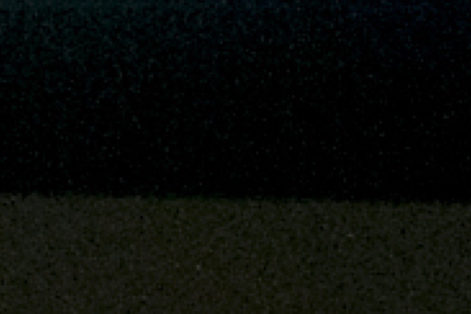 A scientist reviews an array of data points on a large monitor in a darkened laboratory
